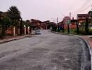 Street view of a residential area with houses and street lights