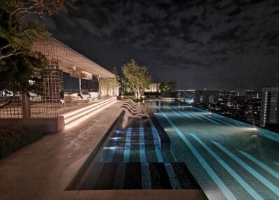 Night view of a rooftop pool with seating area and cityscape