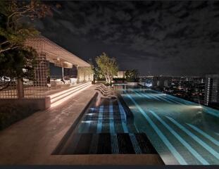 Night view of a rooftop pool with seating area and cityscape