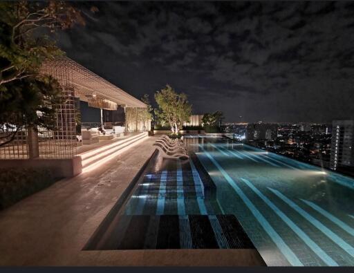 Night view of a rooftop pool with seating area and cityscape