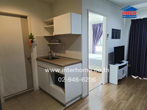 Small kitchen area with adjacent bedroom and living space