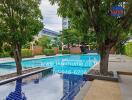 Outdoor swimming pool area with trees and seating