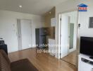 Living room with adjacent kitchen and labeled contact details for the real estate agency