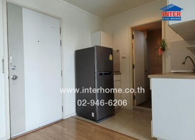 Small kitchen with white cabinets, a stainless steel fridge, and wooden flooring