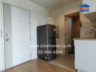 Small kitchen with white cabinets, a stainless steel fridge, and wooden flooring