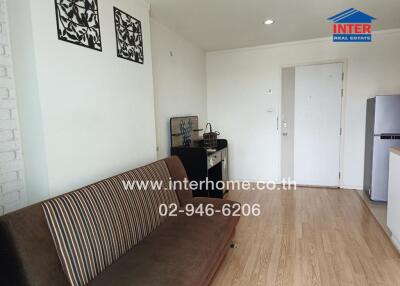 Living room with a sofa, wooden floor, wall decor, and entrance door