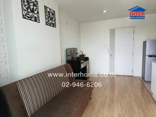 Living room with a sofa, wooden floor, wall decor, and entrance door