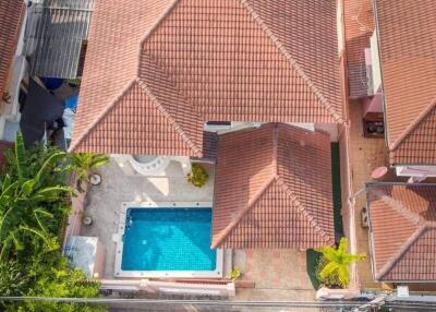 Aerial view of a house with a red-tiled roof and a swimming pool