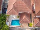 Aerial view of a house with a red-tiled roof and a swimming pool