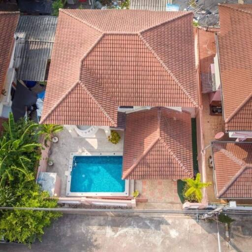 Aerial view of a house with a red-tiled roof and a swimming pool