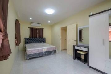 Spacious bedroom with bed, wardrobe, vanity table, and air conditioning