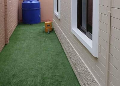 Side yard with artificial grass and blue water tank