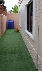 Side yard with artificial grass and blue water tank