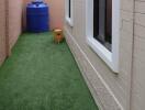 Side yard with artificial grass and blue water tank