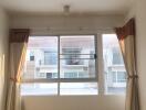 Bright and empty main living space with large windows and curtains