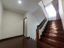 Interior staircase with dark wooden steps and a curtain-covered window