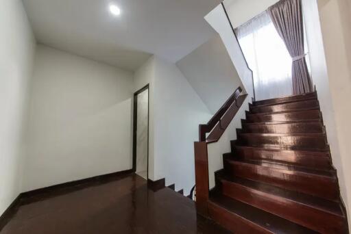 Interior staircase with dark wooden steps and a curtain-covered window