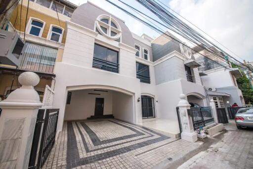 Front facade of a multi-story residential building with driveway and gated entrance