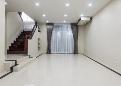 Spacious living room with stairs, large window, and modern lighting