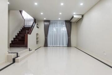 Spacious living room with stairs, large window, and modern lighting