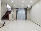 Spacious living room with stairs, large window, and modern lighting