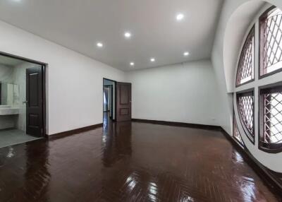 Spacious bedroom with wooden flooring and large windows