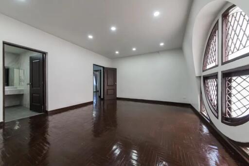 Spacious bedroom with wooden flooring and large windows