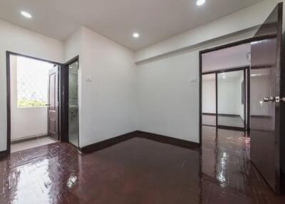 Spacious bedroom with polished wooden floor and bathroom access