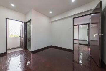 Spacious bedroom with polished wooden floor and bathroom access