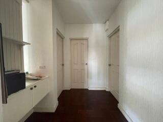 Hallway with three doors and a built-in shelf unit