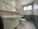 Modern bathroom with a vanity, toilet, and window