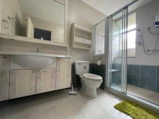 Modern bathroom with large mirror, vanity sink, toilet, and walk-in shower