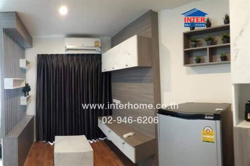 Modern decorated living room with shelves, air conditioner, and a refrigerator