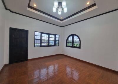 Bright and spacious bedroom with hardwood flooring and modern lighting fixture