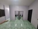 Bathroom with two toilets and green-patterned floor tiles