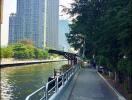 Riverside walking path with high-rise buildings in the background