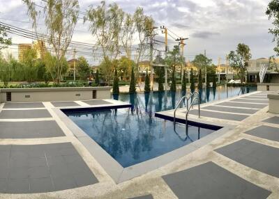 Outdoor swimming pool area with surrounding trees and buildings.