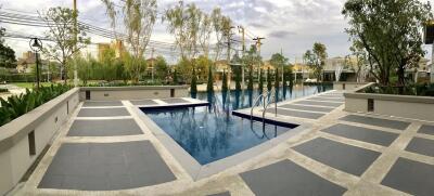 Outdoor swimming pool area with surrounding trees and buildings.