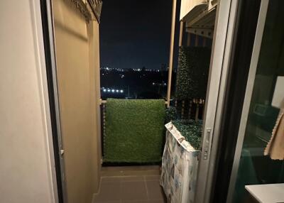 Small balcony view at night with green artificial grass and laundry area