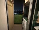 Small balcony view at night with green artificial grass and laundry area