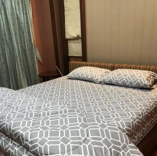 Bedroom with a double bed, patterned bedsheet, and pillows