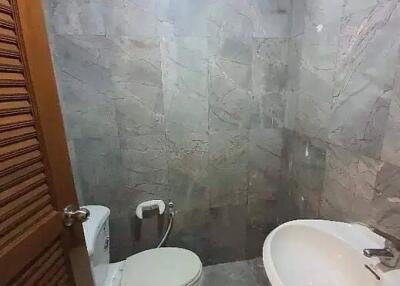 Modern bathroom with marble tiles, sink, and toilet