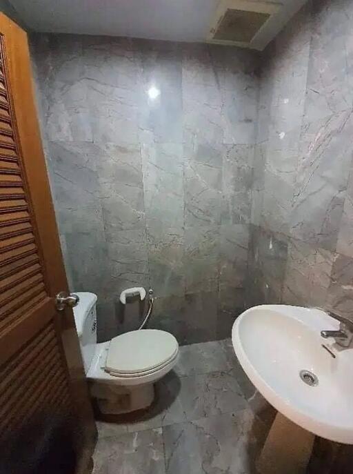 Modern bathroom with marble tiles, sink, and toilet