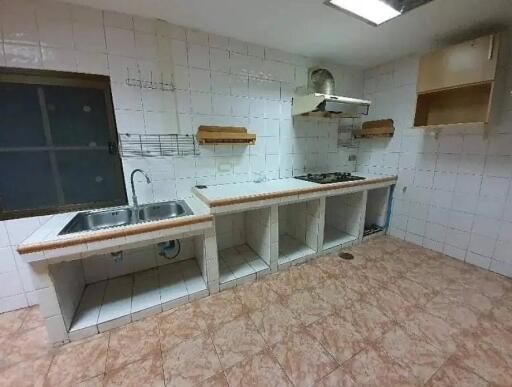 Empty kitchen with tiled surfaces, sink, and stove.