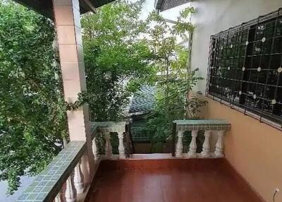 A balcony with tiled floor and railing overlooking trees