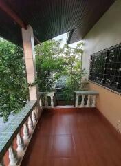 A balcony with tiled floor and railing overlooking trees