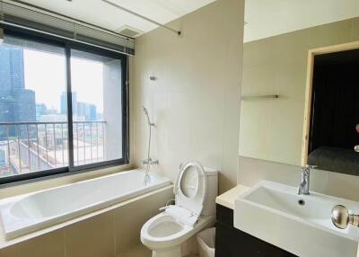 Modern bathroom with large window, bathtub, toilet, sink, and mirror