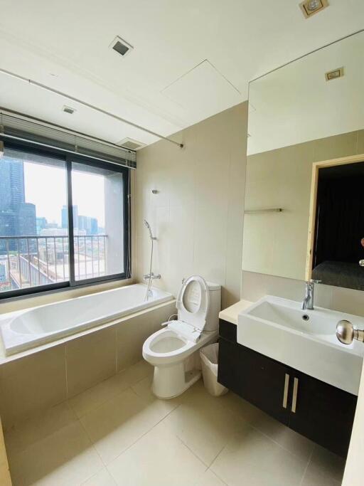 Modern bathroom with large window, bathtub, toilet, sink, and mirror
