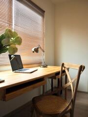 A tidy home office desk with a laptop, lamp, and a chair.