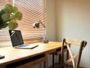 A tidy home office desk with a laptop, lamp, and a chair.